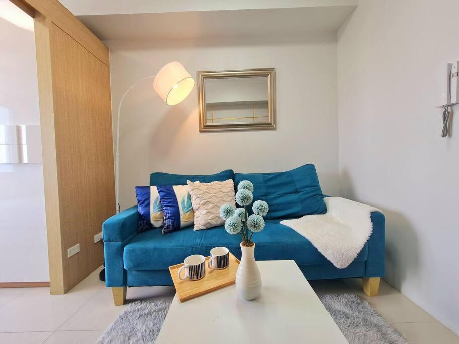 een woonkamer met een blauwe bank en een tafel bij Grass Residences T4 383 in Manilla
