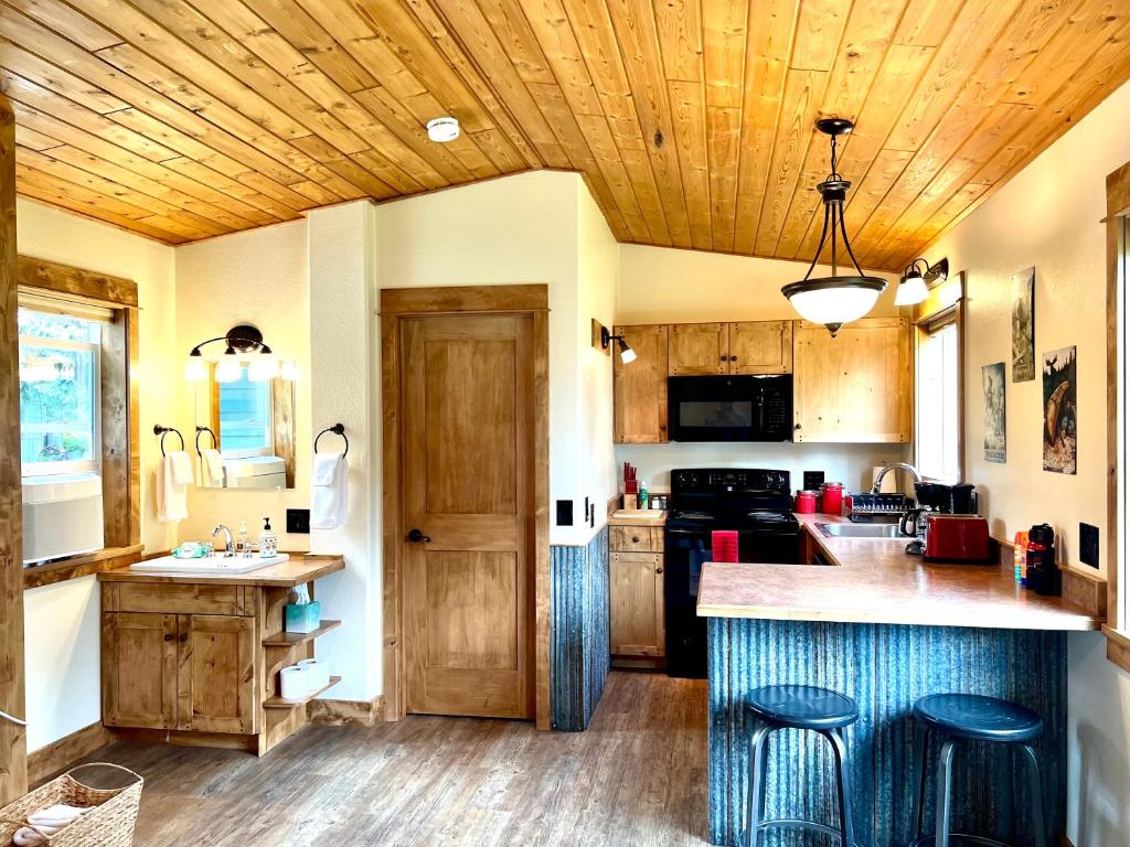 a kitchen with wooden ceilings and a kitchen island with stools at Glacier's Edge Cabins in Columbia Falls