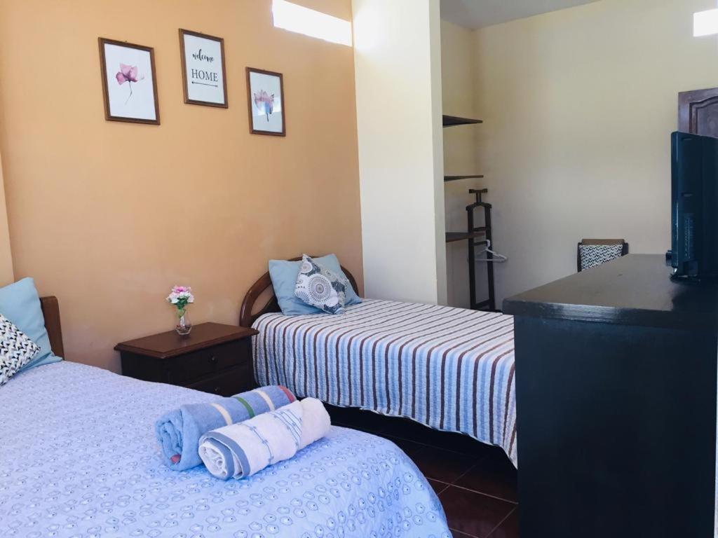 a hotel room with two beds and a television at Bonita casa acogedora in Cochabamba