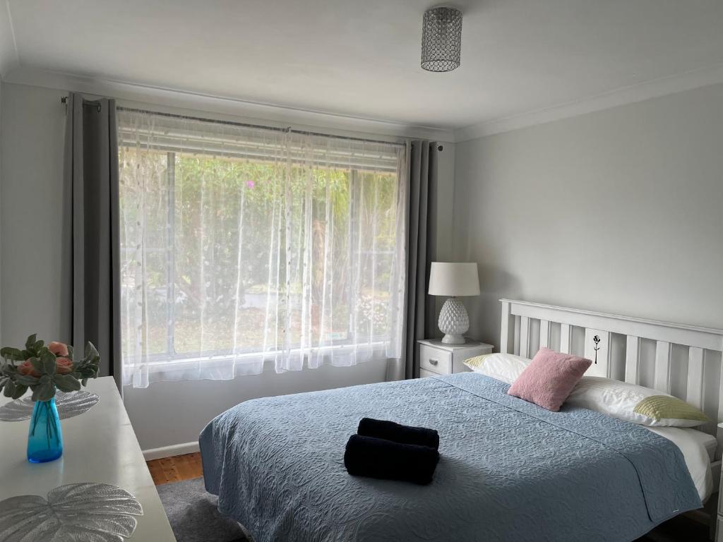 1 dormitorio con cama y ventana grande en Perfectly located house with a big backyard., en Castle Hill