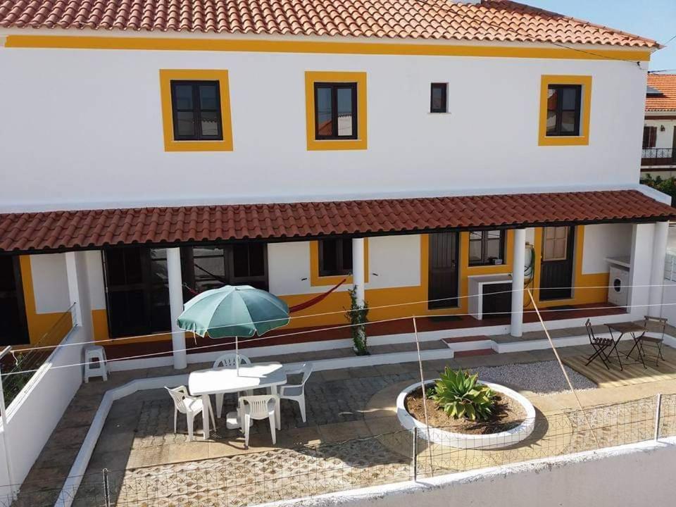 Cette maison dispose d'une terrasse avec une table et un parasol. dans l'établissement Alojamentos Vitinho 3 for Walkers, à Vila Nova de Milfontes