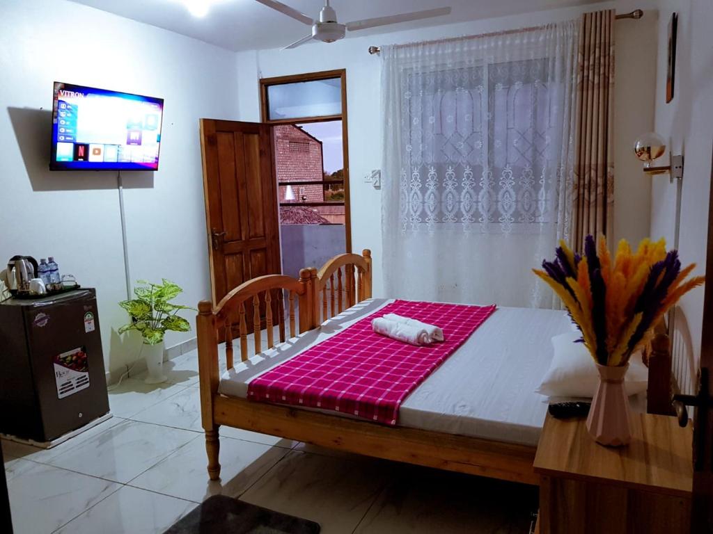 Bett in einem Zimmer mit einem TV und einem Fenster in der Unterkunft Donita's Seaview Apartments in Mombasa