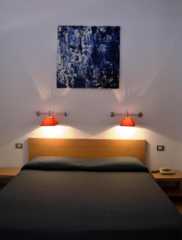 a bedroom with a bed with two lights on it at Hotel Cala Luna in Cala Gonone