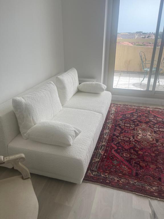 - un canapé blanc dans le salon doté d'une fenêtre dans l'établissement Satine, à Perpignan