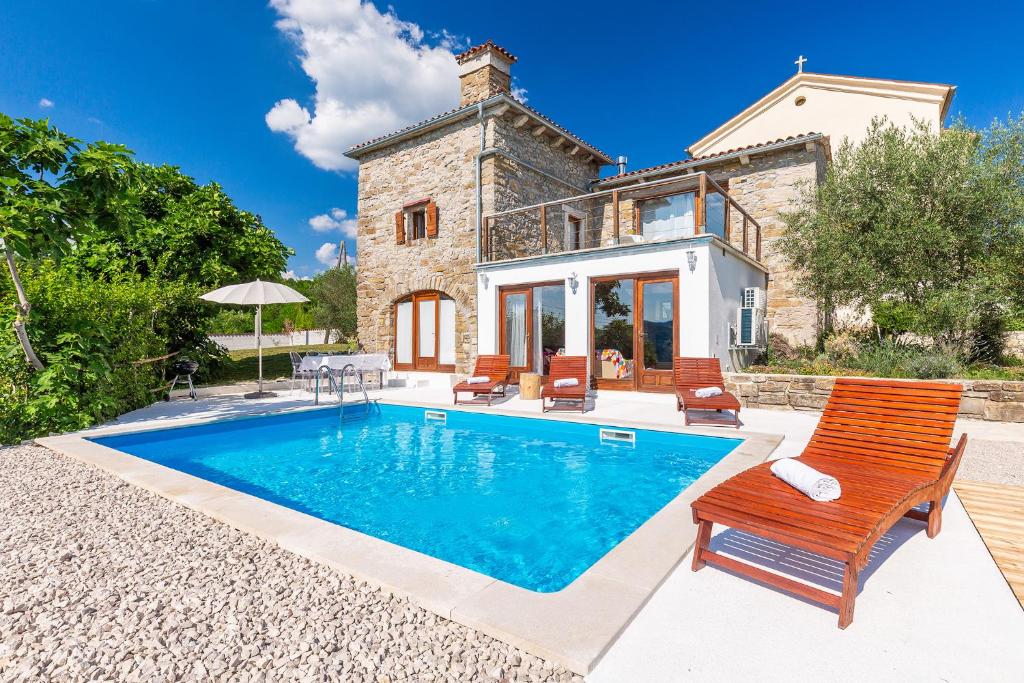 a villa with a swimming pool in front of a house at Sussini in Potpićan