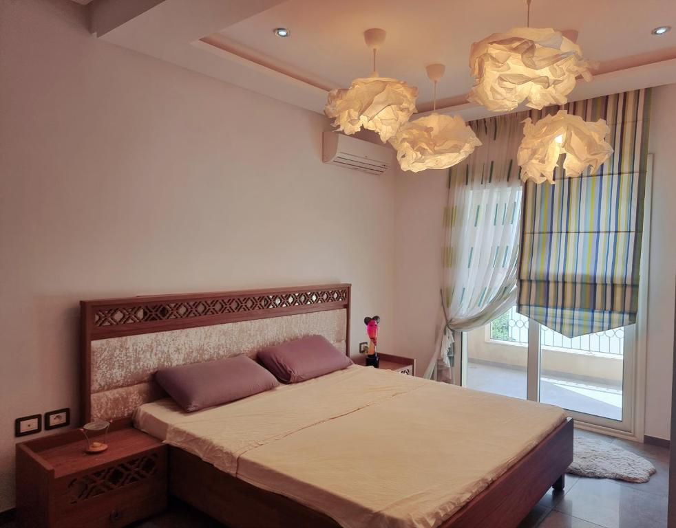 um quarto com uma cama grande e 2 lustres em Apart haut standing v mer em Sousse