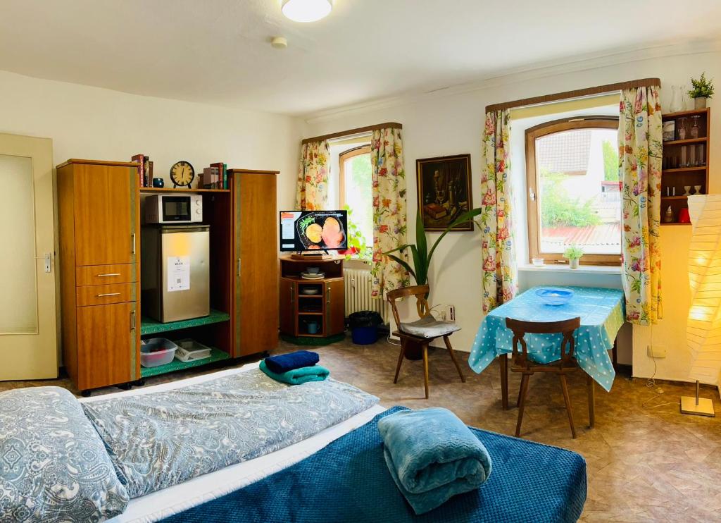 1 dormitorio con cama, mesa y TV en Apartment Amelie - Zimmer mit TV, W-Lan, Mikrowelle und Kühlschrank, Bad mit Dusche, en Malterdingen