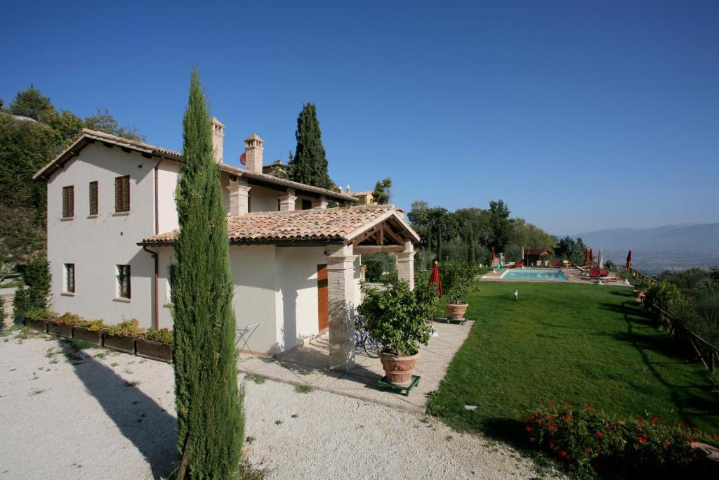 a white house with a yard and a swimming pool at Casa Vacanze Vecciano in Montefalco