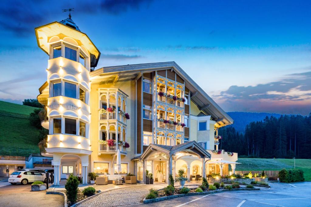 un grand bâtiment avec une voiture garée dans un parking dans l'établissement Hotel Erika, à Braies