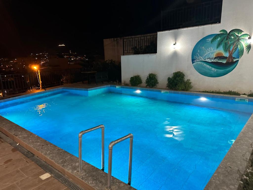 - une piscine la nuit avec une fresque murale sur le côté du bâtiment dans l'établissement VILLA MYRTAJ, à Saranda