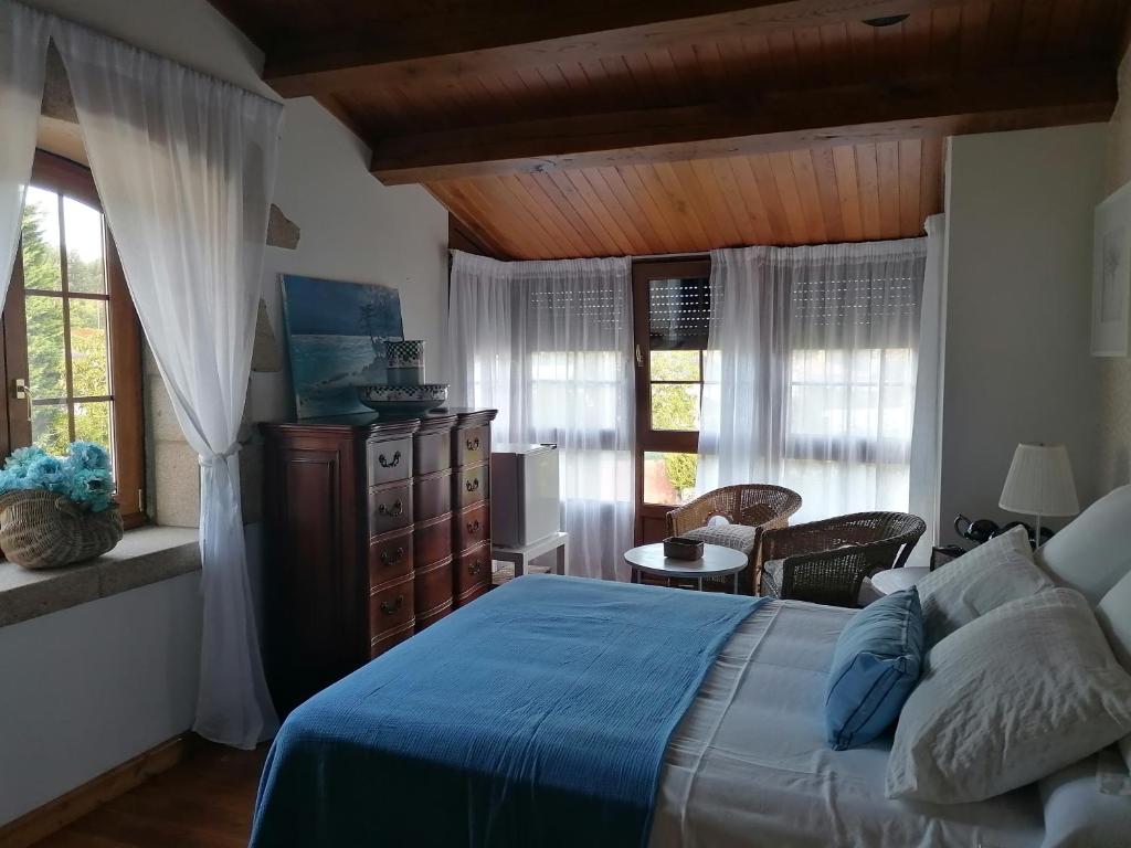 1 dormitorio con 1 cama azul en una habitación con ventanas en Casa Bonita, en Mugardos