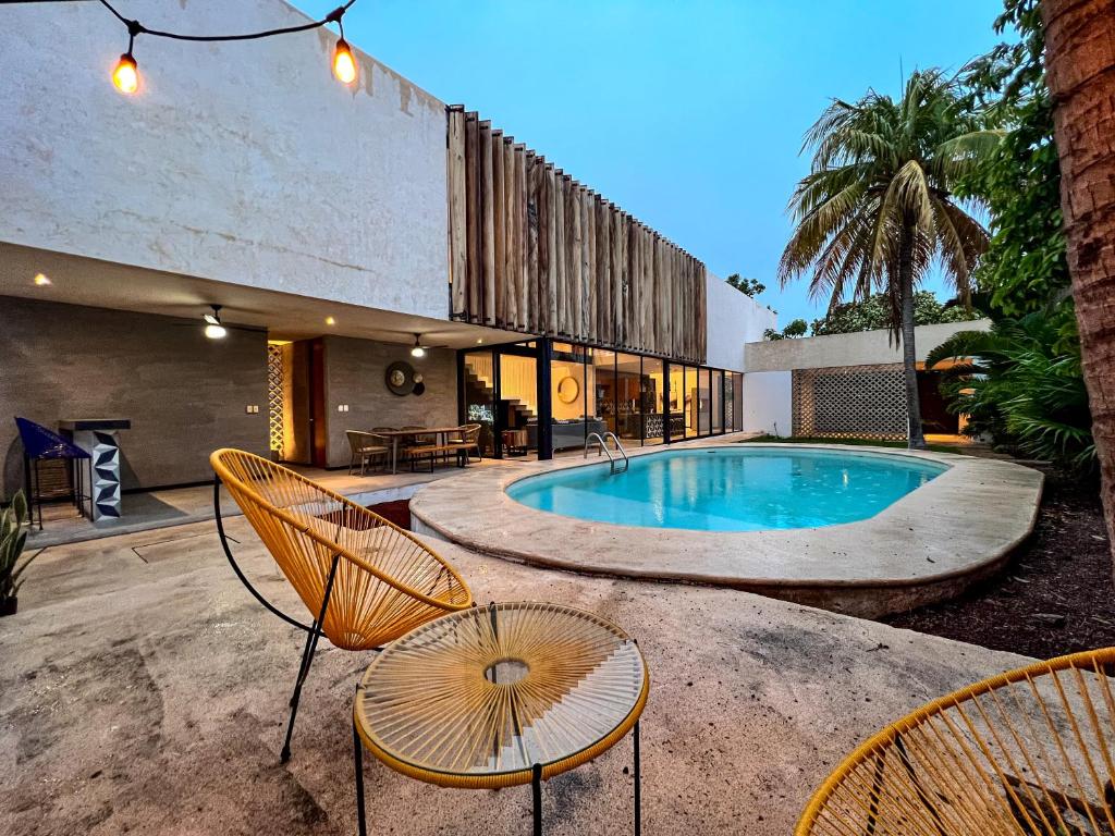 a swimming pool with chairs and a house at Casa Concordia in Mérida