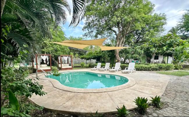 een zwembad met stoelen en een grote parasol bij Hotel Zelen in Tamanique