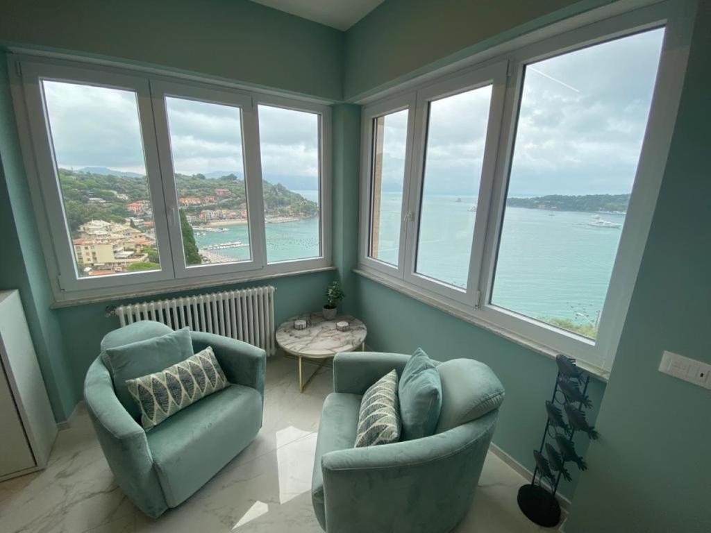 - un salon avec deux chaises et de grandes fenêtres dans l'établissement CaseMaggi Attico sul Mare, Penthouse on the Sea, à Portovenere