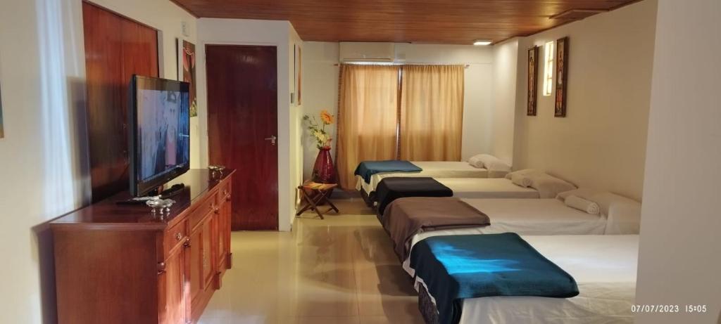 Habitación de hotel con 4 camas y TV de pantalla plana. en Casa Tunez, en Buenos Aires