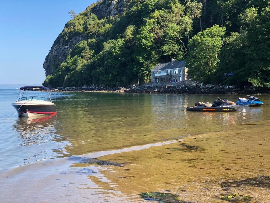 a small boat in the water next to a house at Heddfan - Peaceful Studio 5 mins from Stunning Llanbedrog Beach in Pwllheli