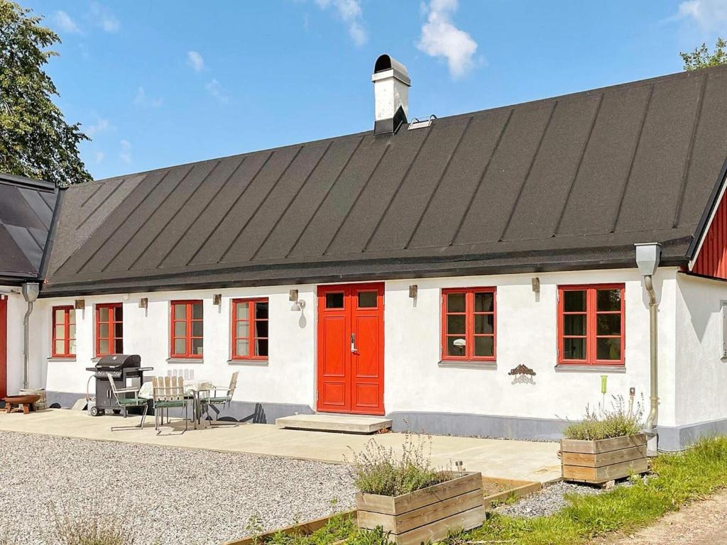 una casa bianca con una porta rossa e un patio di 4 person holiday home in SKURUP a Skurup