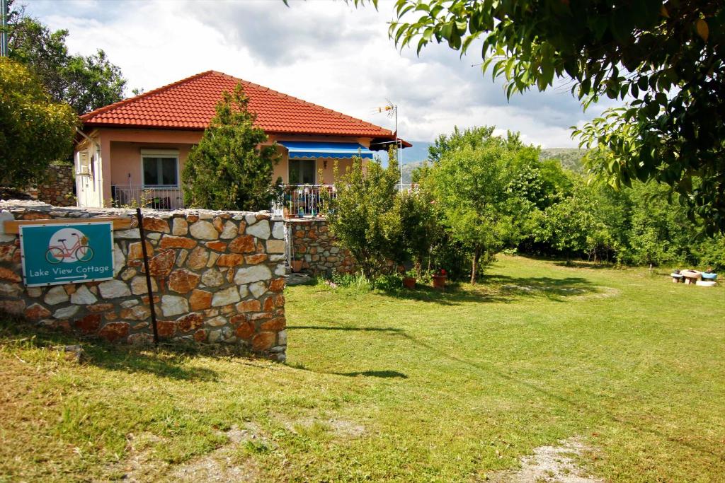 a house with a fence and a stone wall at Countryside Cottage with Garden & Lake View in Peraía