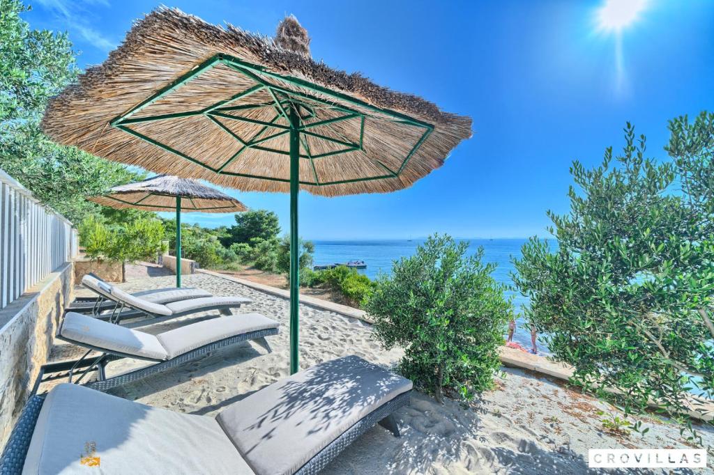 a beach with chairs and an umbrella and the ocean at Stone in Murter