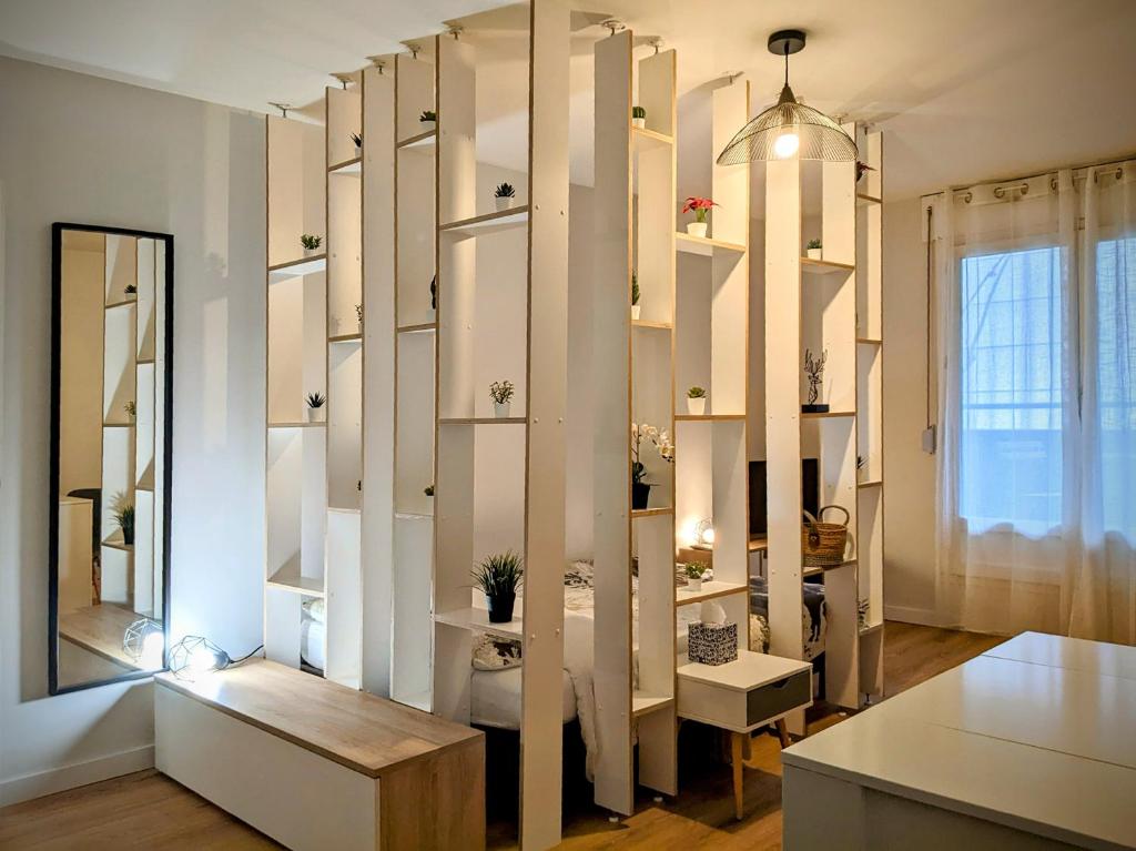 Cette chambre dispose d'étagères blanches, d'une table et d'un miroir. dans l'établissement Logement charmant Charpennes, à Villeurbanne