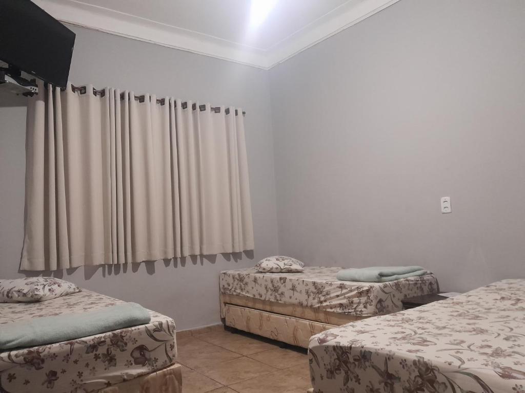 een kamer met 2 aparte bedden en gordijnen bij Pousada Vitória in Aparecida