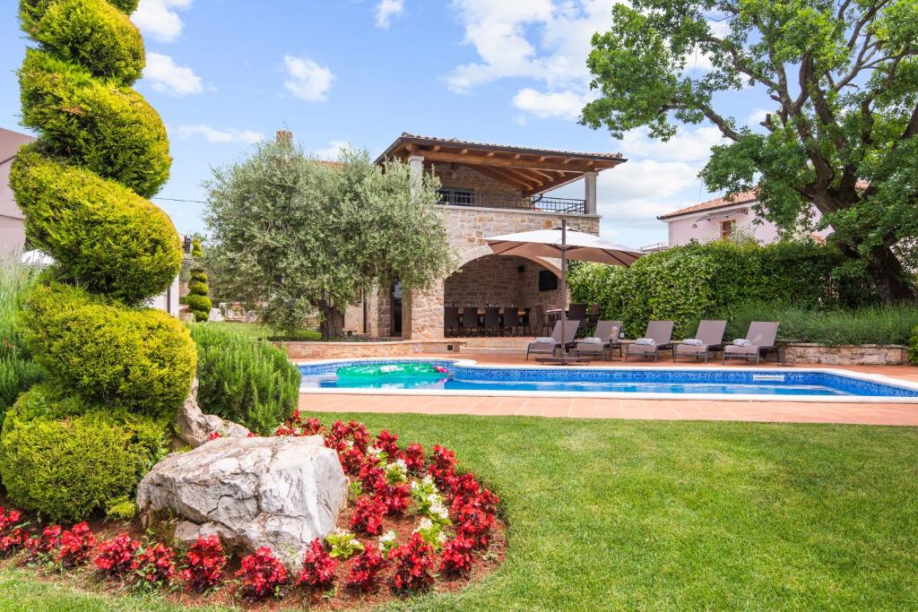 a house with a swimming pool and a garden with flowers at Pilato in Vižinada