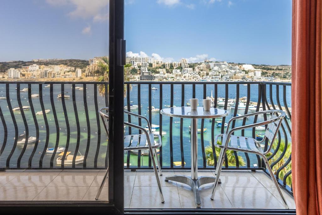 d'un balcon avec une table et des chaises et une vue sur l'eau. dans l'établissement Adorable Seaview apt at St Paul's Bay, à San Pawl il-Baħar