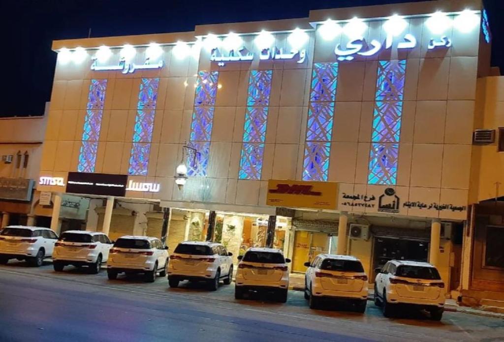 um grupo de carros estacionados em frente a um edifício em ركن داري للشقق المخدومة em Al Majmaah