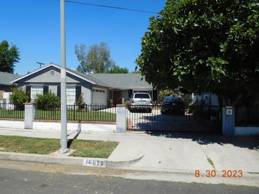 una casa con una valla y un coche aparcado en una entrada en Nice Northridge 4-2-2 Pool home near CSUN and Pierce College en Northridge