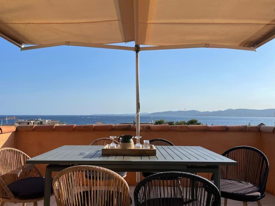 - une table avec des chaises et un parasol sur le balcon dans l'établissement Saint Raphaël, Terrasse, superbe vue mer, à Saint-Raphaël
