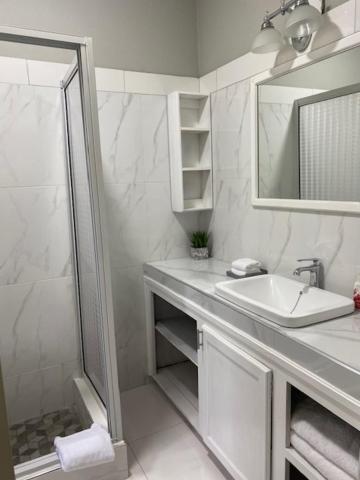 a white bathroom with a sink and a shower at Runthings Hideaway Stay Negril in Negril