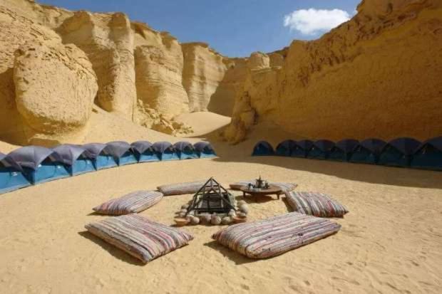 a group of tents on the sand in the desert at El Camel Hotel in Bawiti
