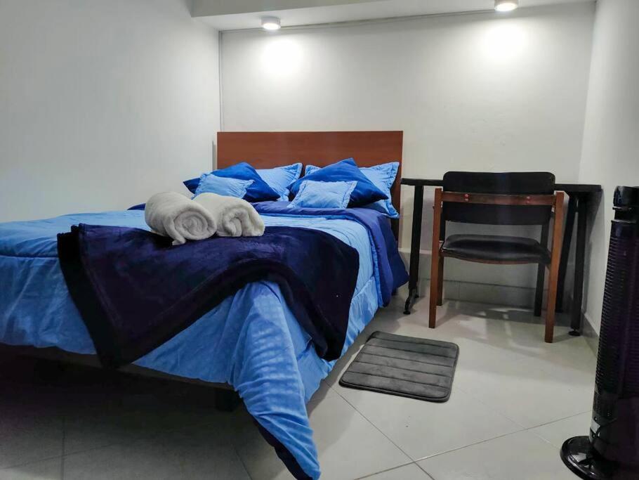 1 dormitorio con 1 cama con silla y 1 cama con sábanas azules en Fresco Aparta estudio Envigado 101, en Envigado