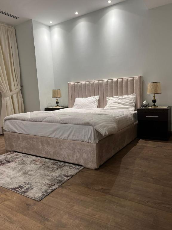 a bedroom with a large bed with two night stands and two lamps at full luxury one bed apartment with maid room penta square in Lahore