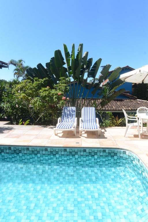 duas cadeiras azuis e brancas sentadas ao lado de uma piscina em Casa Franco Hospedaria em Trancoso