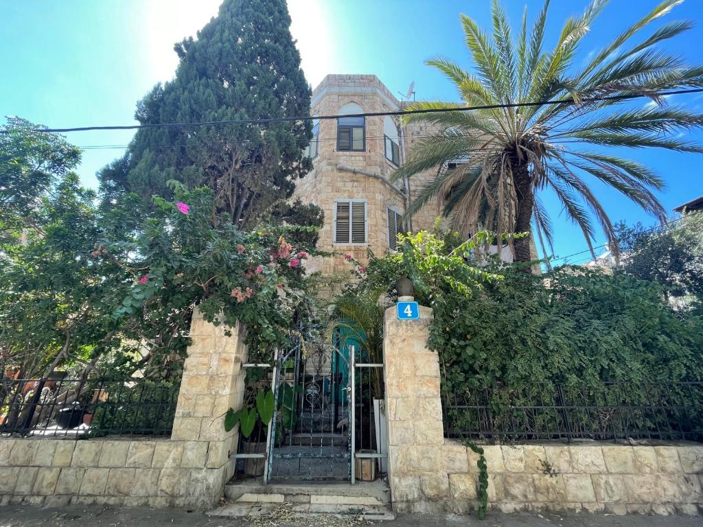 an old house with a gate and a palm tree at Villa Marina in Haifa