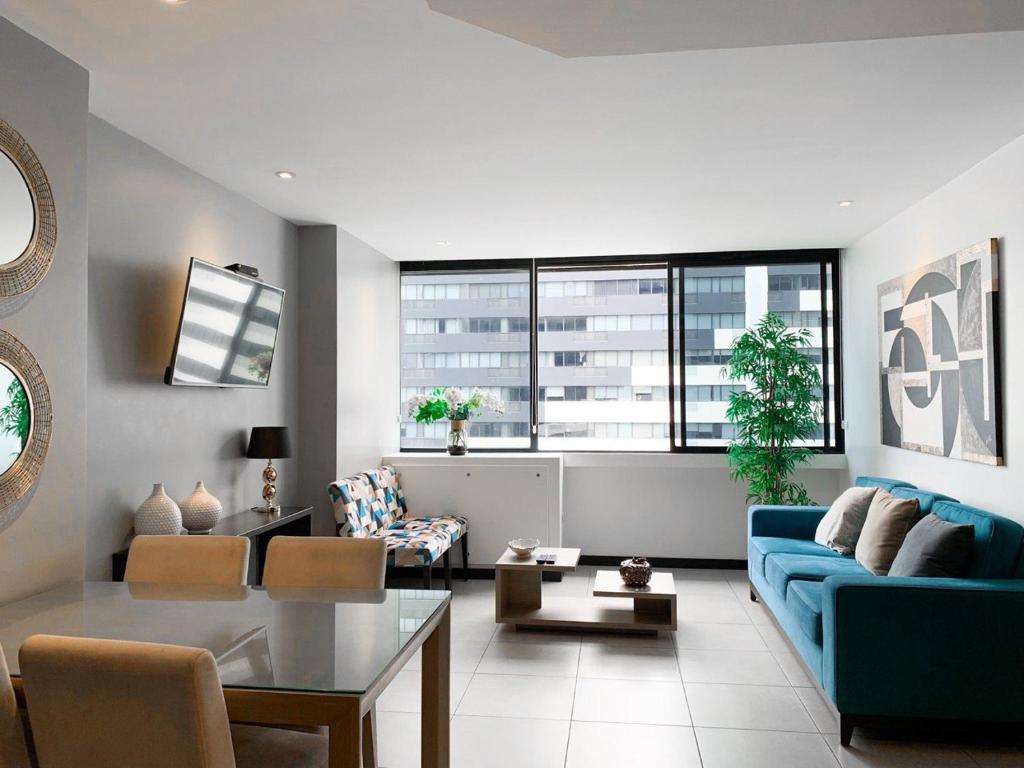 a living room with a blue couch and a table at Penthouse de 2 habitaciones con vista al rio y parking in Guayaquil