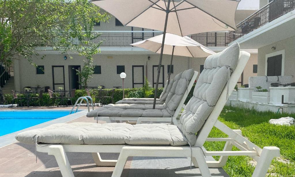 two lounge chairs and an umbrella next to a pool at Ermis Hotels & Resorts in Lygia