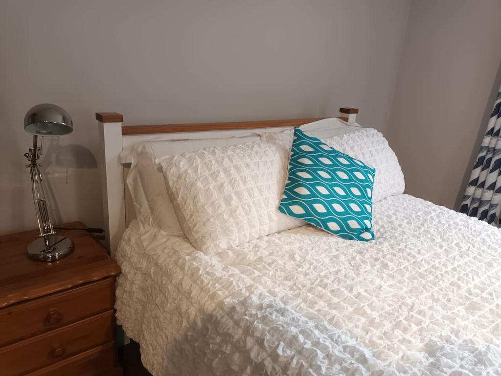uma cama com uma almofada azul em cima em Tummock Studio perfect for exploring the North coast em Kilraghts