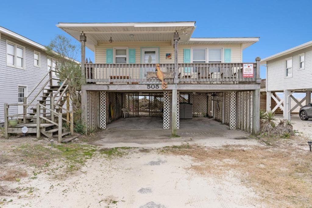 a house with a large deck in front of it at Yellow Bird in Holden Beach