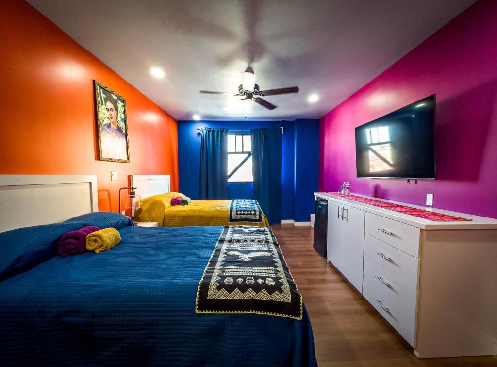 a bedroom with two beds and a flat screen tv at Hotel Cantaritos in Rosarito