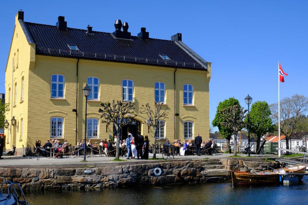 a group of people standing outside of a yellow building at Det Lille Hotel in Risør