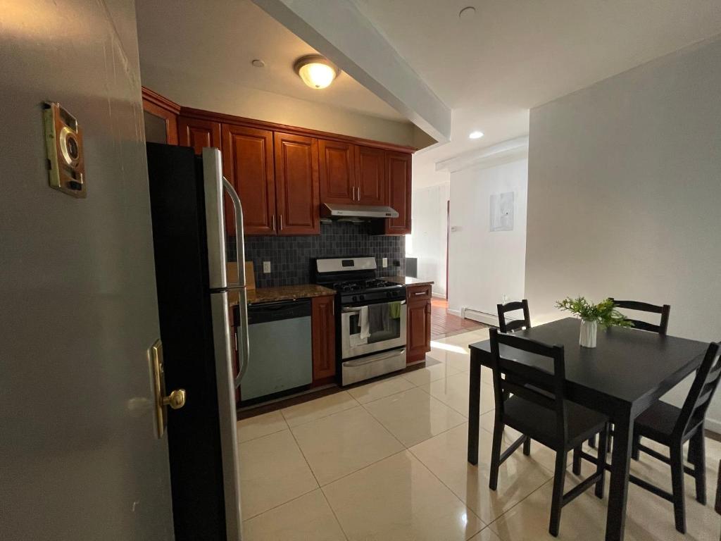 a kitchen with a table and chairs and a refrigerator at 2BR elevator APT 10min to LGA airport 1min to train! in Queens