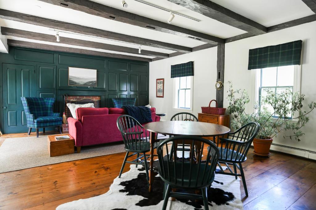 uma sala de estar com um sofá vermelho e uma mesa em 1820 House - VT Charm + Modern Comforts + Hot Tub em Stowe