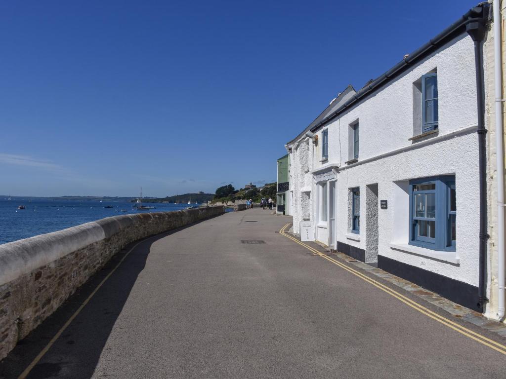 an empty street next to a wall and the water at Prydes Cottage in Saint Mawes