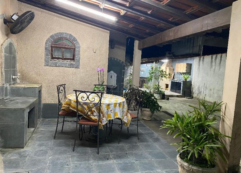 einen Tisch und Stühle auf einer Terrasse mit einem Tisch und einem Tisch in der Unterkunft Lar de PAZ in São Pedro da Aldeia