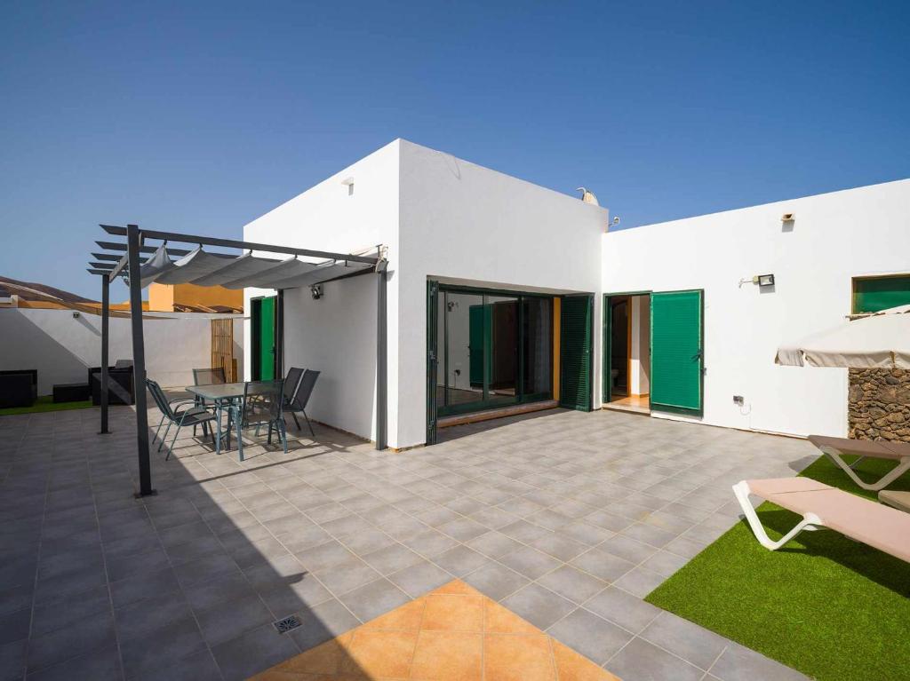 una casa bianca con patio arredato con sedie e tavoli di Mahostly Casa Fika a Corralejo