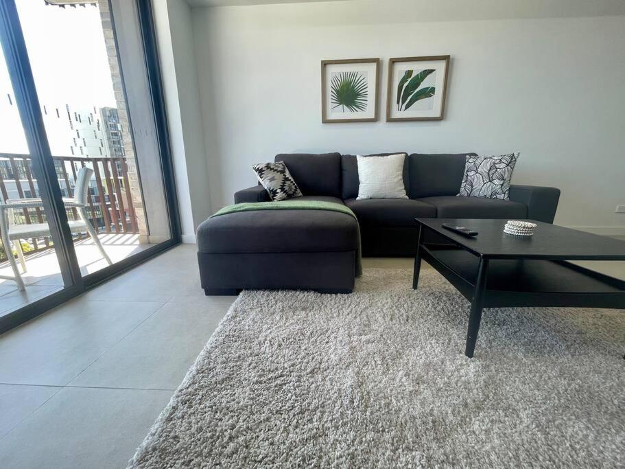 a living room with a couch and a table at Cosy Stays 1 Bedroom Apartment Rosebery Parking & Balcony Sydney Escape in Sydney