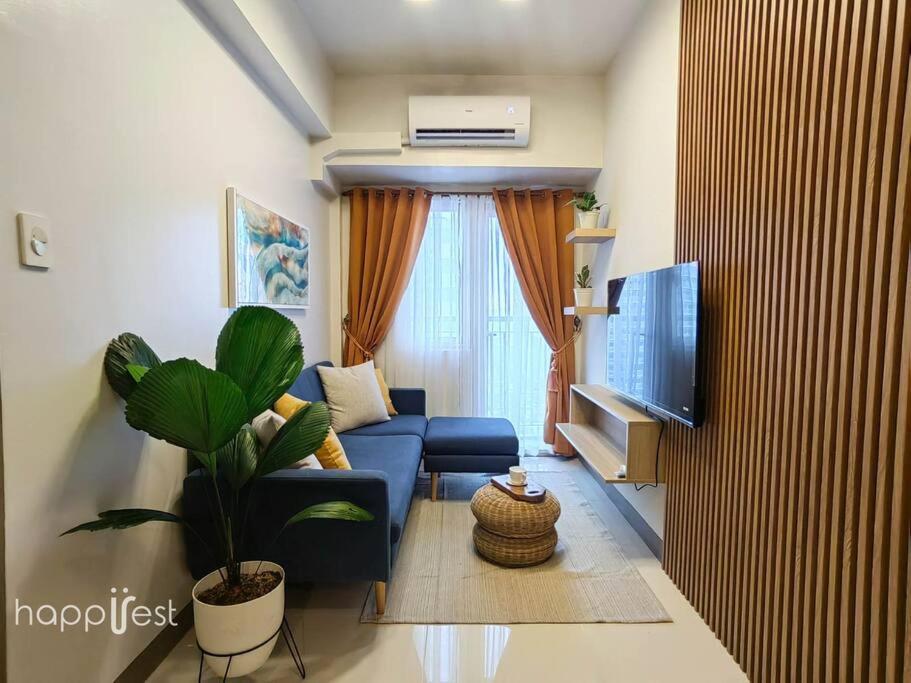een woonkamer met een blauwe bank en een tv bij Happirest at Coast Residences, Pasay - 1 Bedroom with Balcony in Manilla