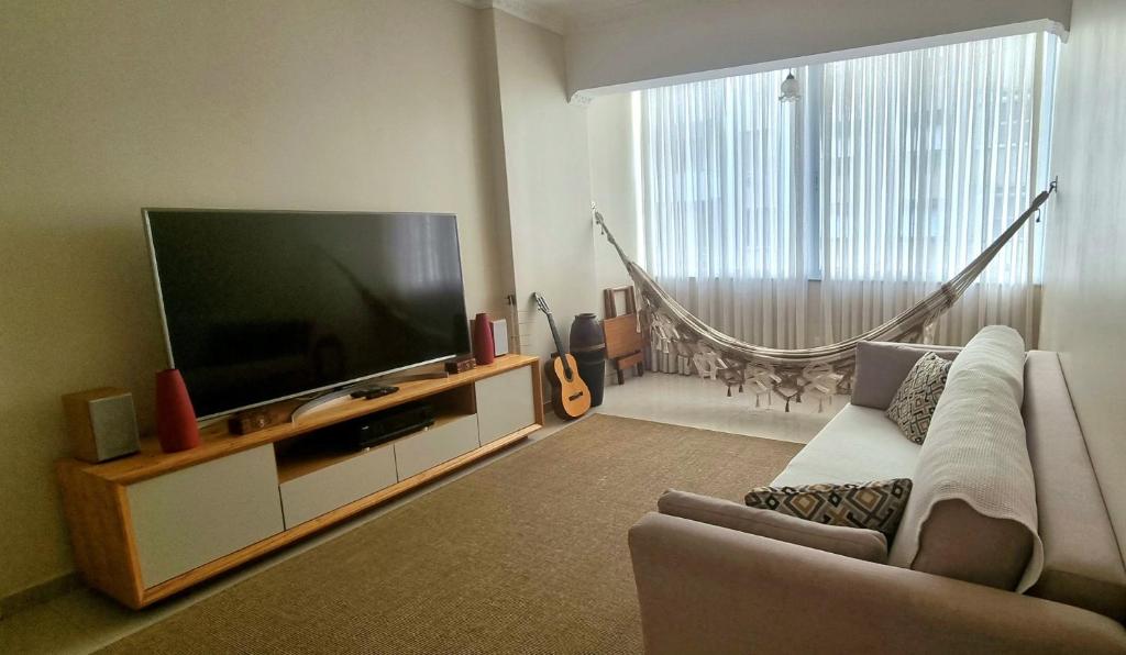 ein Wohnzimmer mit einem Sofa und einem großen Flachbild-TV in der Unterkunft Confortável apartamento em Copacabana in Rio de Janeiro